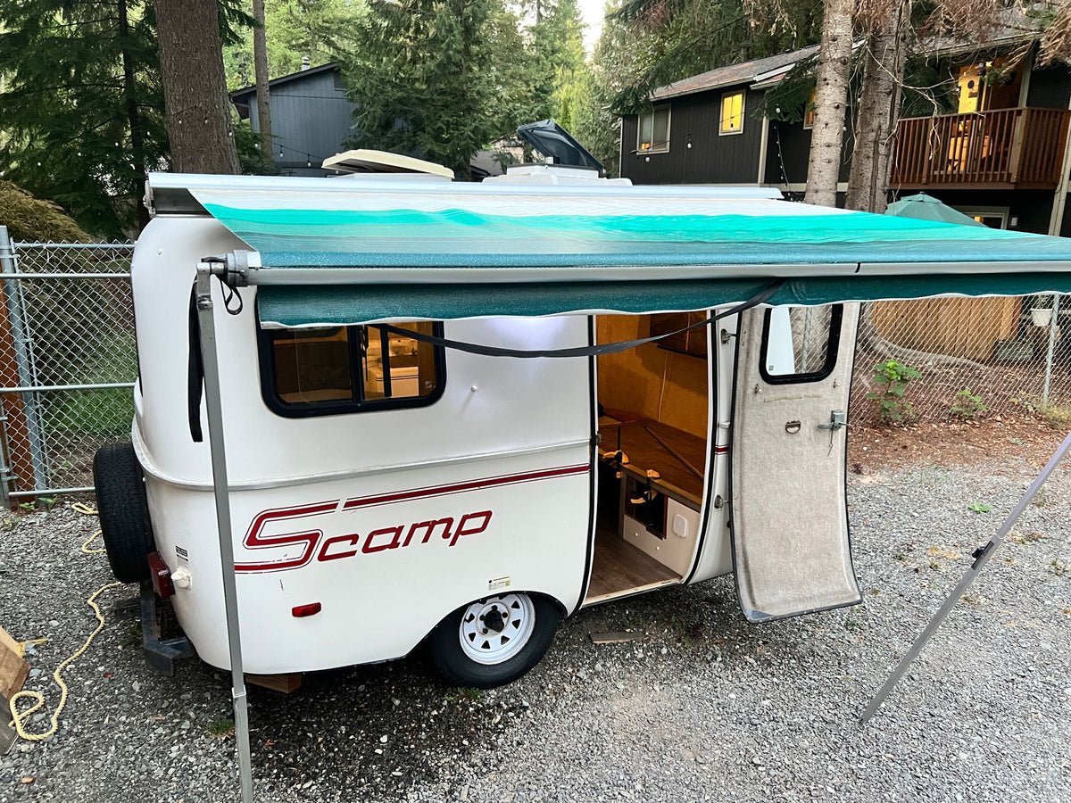 White Scamp compact travel trailer with extended awning, parked on gravel. Great for an RV rental getaway! — photo 17
