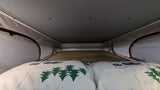 Cozy sleeping area in an RV rental, featuring a bed with tree-patterned pillows and a pop-top roof, perfect for mobile adventures.