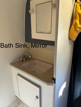 RV rental interior: compact bath sink with faucet, mirror, and storage cabinet. Practical amenities for your journey.
