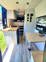 Cozy RV rental interior with modern kitchen, dinette, and sleeping area. Enjoy comfortable mobile living in this converted van.