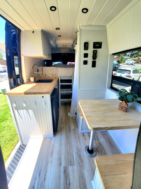 Cozy RV rental interior with modern kitchen, dinette, and sleeping area. Enjoy comfortable mobile living in this converted van.
