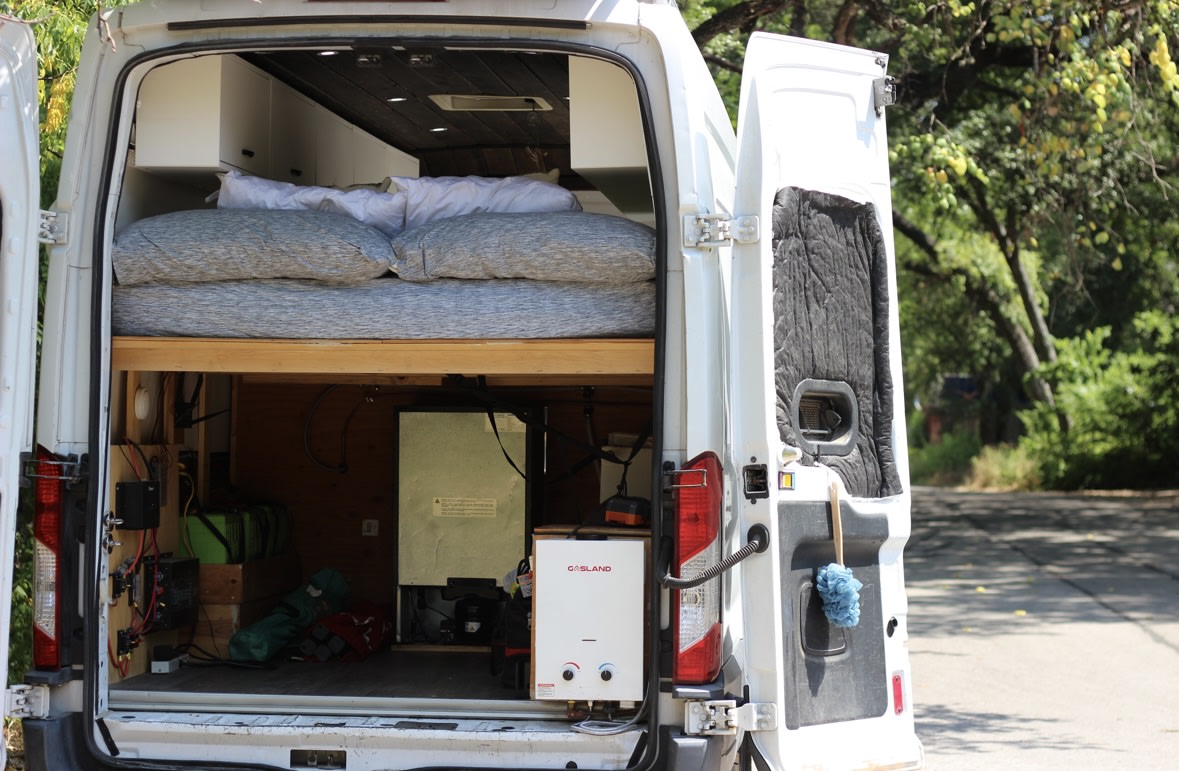  open side door reveals interior. Texas PPG-4130.|Compact RV rental kitchen featuring a black stove and oven unit with visible control knobs — photo 4