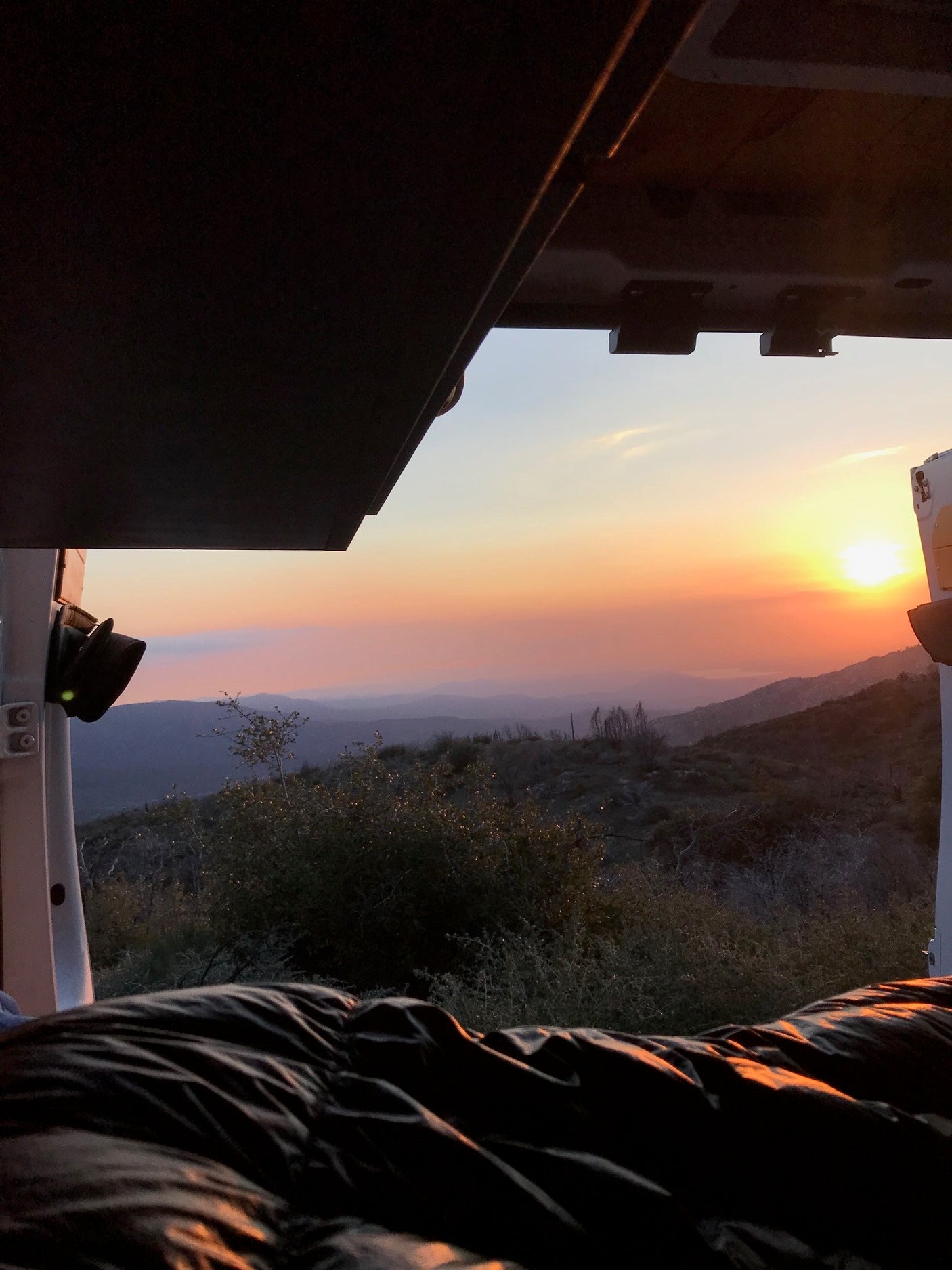 View from an RV rental: a serene mountain sunset painting the sky. Cozy inside, overlooking the scenic vista, perfect for travel.
