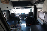 rv rental: Inside a Mercedes-Benz Sprinter camper van, looking forward. Features swivel seats, dashboard, and integrated living space.