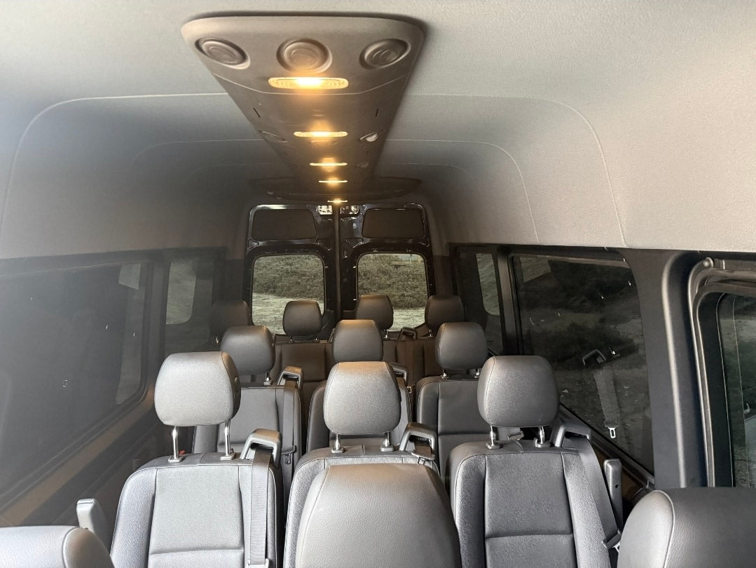 Inside a modern rv rental passenger van. Rows of dark seats under bright overhead lights await group travel adventures. — photo 7