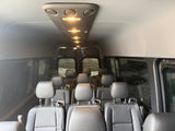 Inside a modern rv rental passenger van. Rows of dark seats under bright overhead lights await group travel adventures.