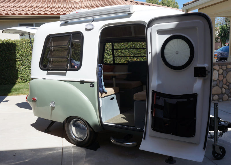 This compact, stylish camper trailer, perfect for RV rental, shows its open door and cozy interior for travel. — photo 9