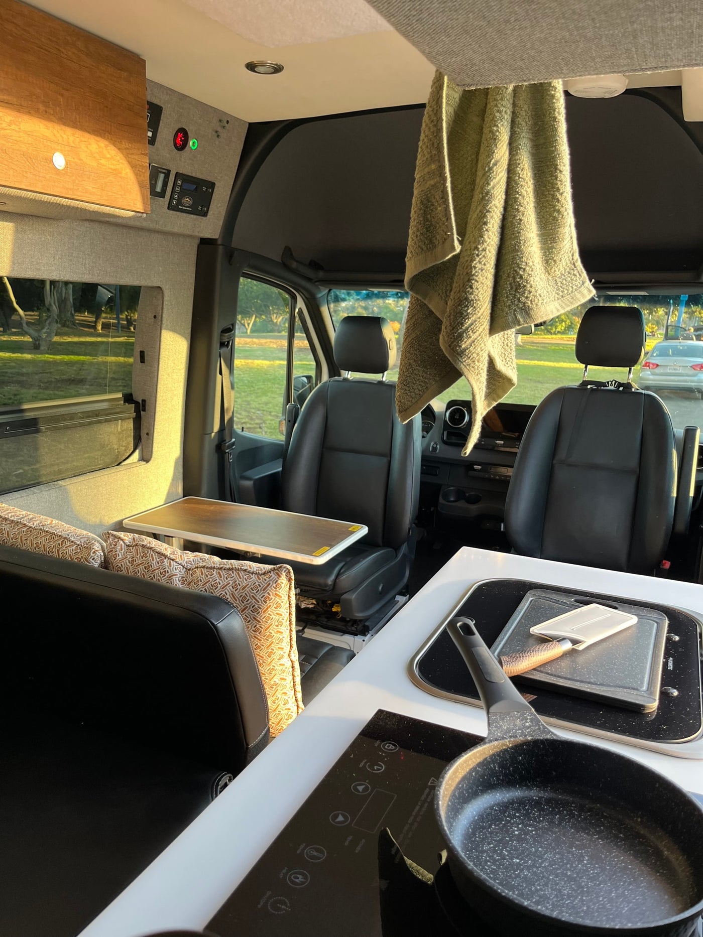 Spacious RV rental interior: front cockpit, side seating with table, and kitchen with induction cooktop. Perfect camper van living. — photo 8