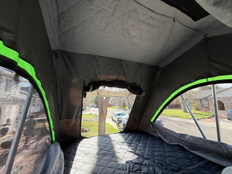 Inside a comfortable rooftop tent with a quilted mattress and street view. Ideal for your next RV rental adventure.