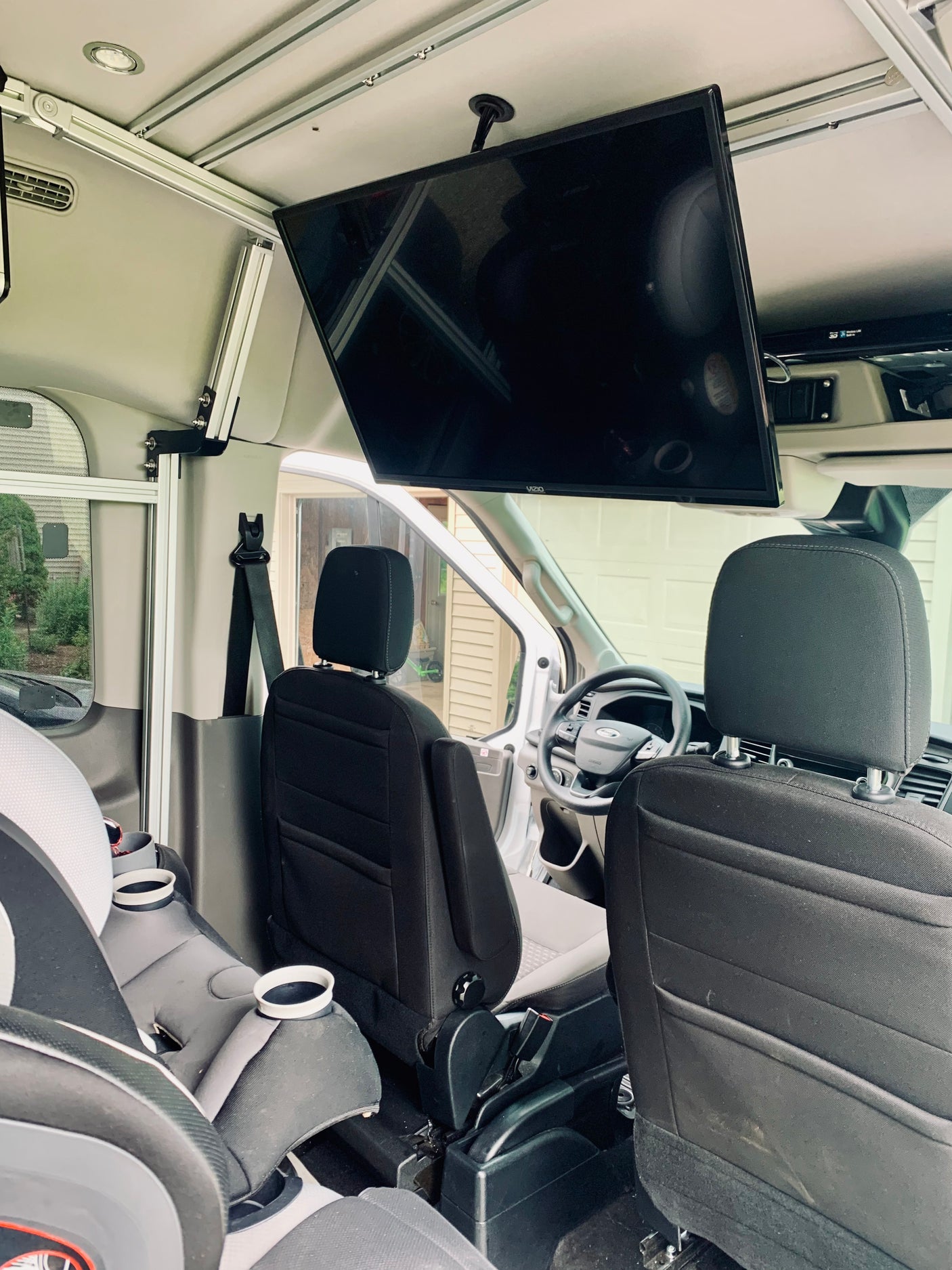 Spacious RV rental interior featuring a large overhead TV and child safety seat, perfect for comfortable family travel.