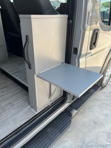 This RV rental van conversion features a convenient fold-out table at the open side door, ideal for camping and outdoor activities.