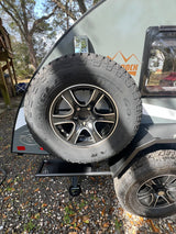 This rugged teardrop RV rental features a prominent Goodyear Wrangler spare tire, perfect for your outdoor adventures.