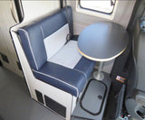 An RV rental's dinette area: blue/white bench seat, black round table, and seatbelt for travel.