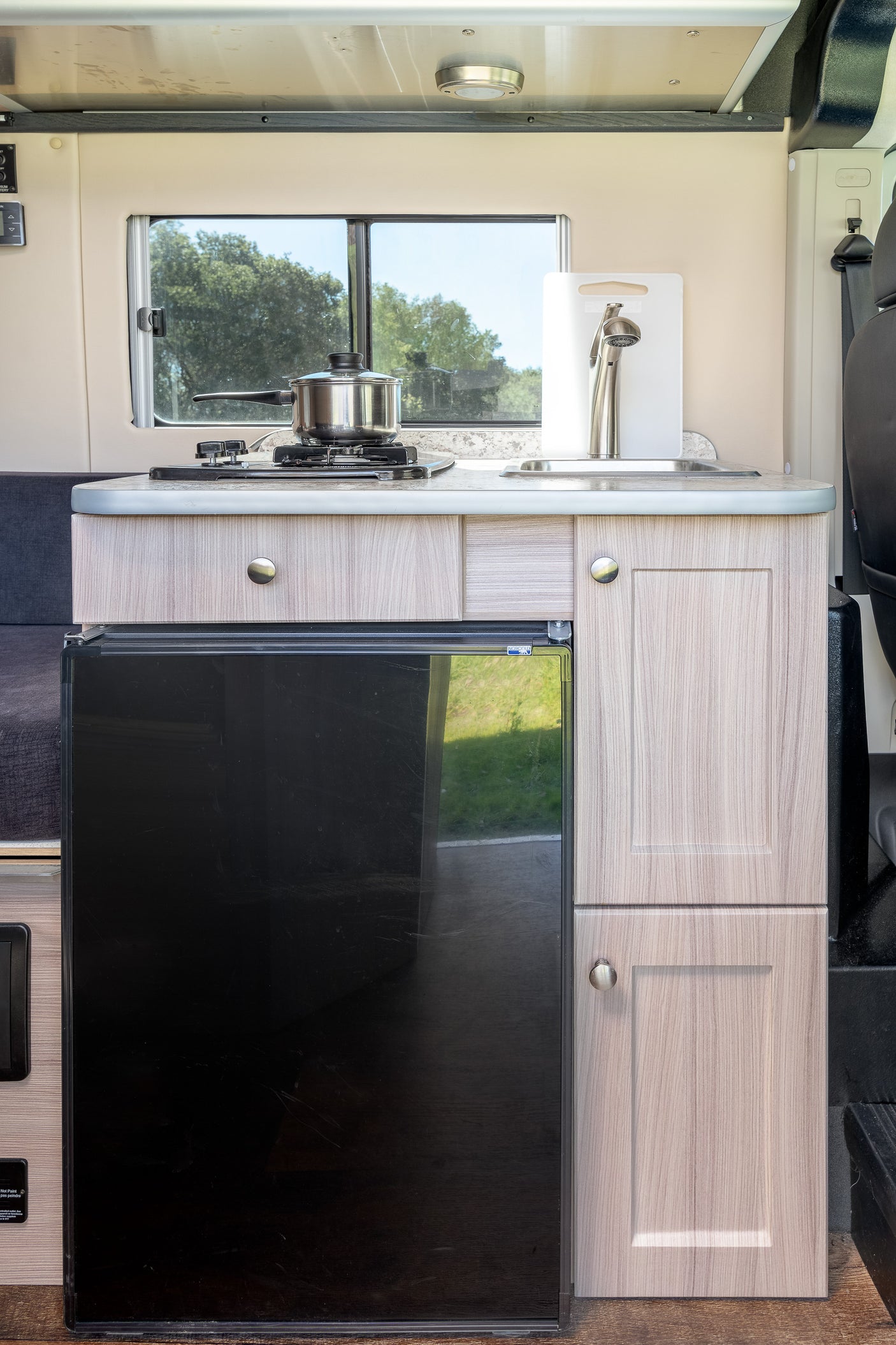 This RV rental's kitchen boasts a compact stove, sink, and fridge, offering essential amenities for comfortable travel.