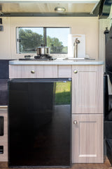 This RV rental's kitchen boasts a compact stove, sink, and fridge, offering essential amenities for comfortable travel.