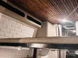Explore this RV rental's cozy interior, featuring a wooden slatted ceiling, a bunk bed, and stylish white brick-patterned walls.