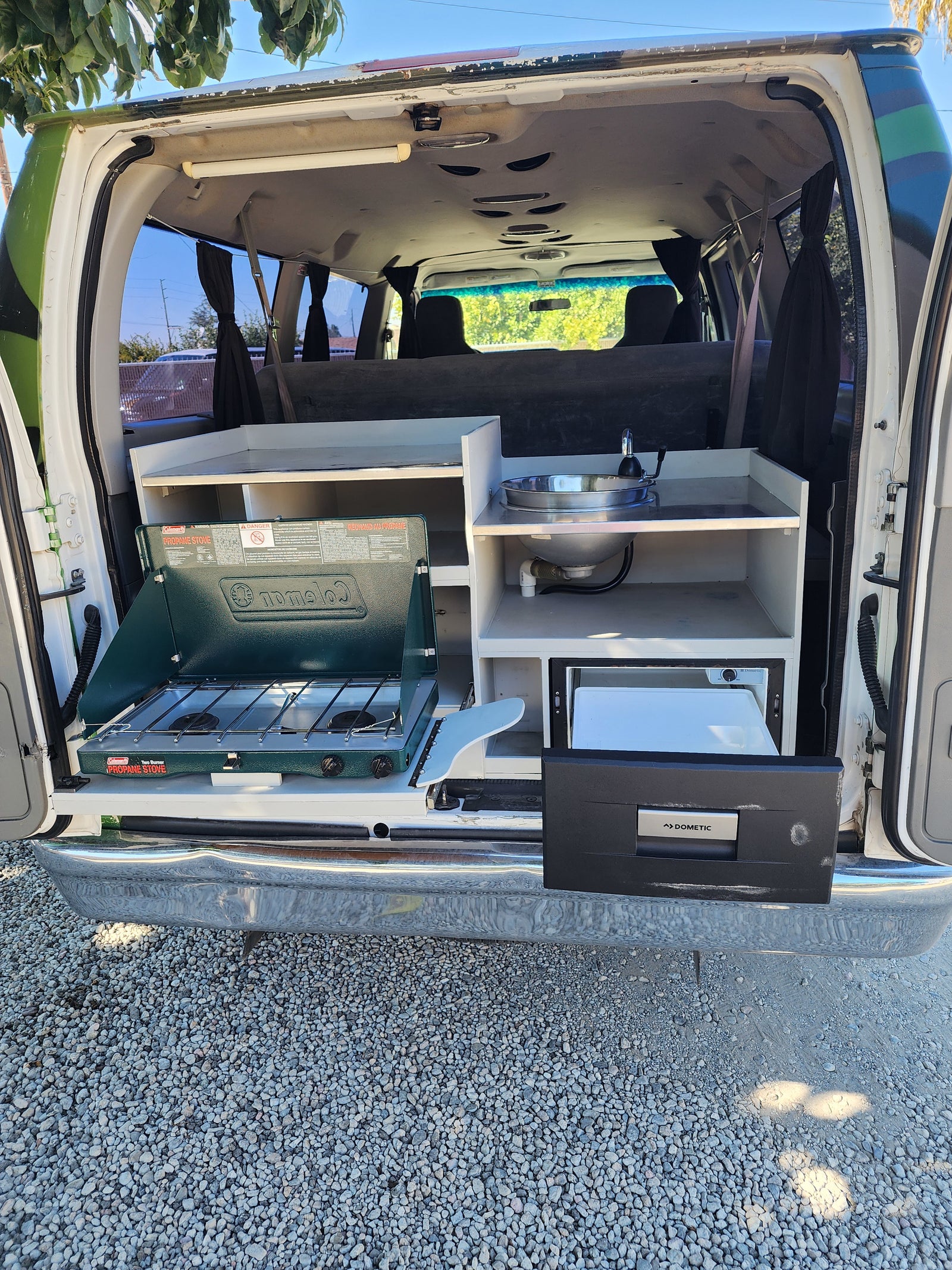 Explore with our RV rental camper van! Features a pull-out kitchen: Coleman stove, sink, and Dometic fridge.