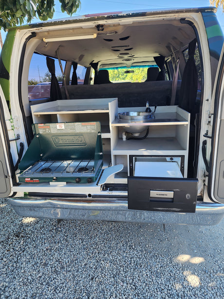 Explore with our RV rental camper van! Features a pull-out kitchen: Coleman stove, sink, and Dometic fridge.