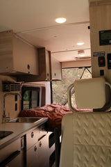 Inside an rv rental: a well-designed camper van interior with a kitchen, sink, cabinets, and rear bed for comfortable living.