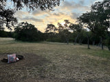 RV rental camping: serene campsite at sunset with a fire pit & picnic table in a natural setting.