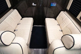 Luxury RV rental interior: facing cream leather seats with quilted patterns, modern controls, and wood paneling.