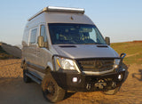 Front view of a customized, light-tan Mercedes Sprinter camper van, equipped for off-road RV rental adventures.