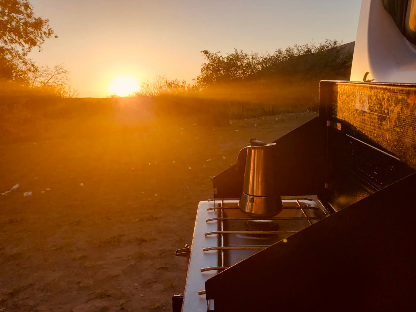 RV rental adventure: Golden sunrise illuminates a Moka pot on an outdoor stove, perfect for camping mornings.