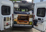 Rear view of an RV rental camper van, revealing its cozy interior with a bed, under-bed storage, and organized equipment.