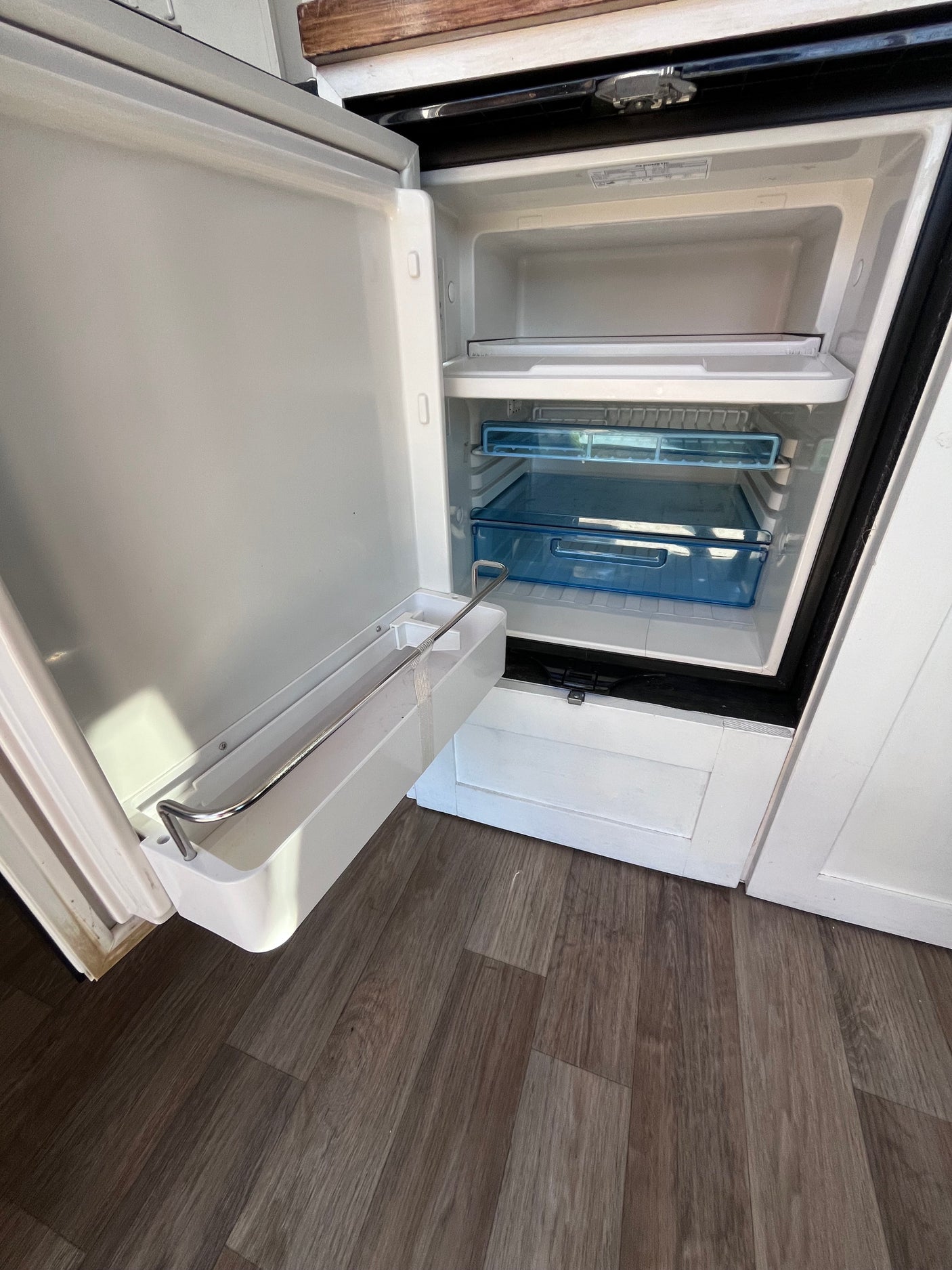 Open RV rental refrigerator, showcasing clean interior, shelves, and door storage. Perfect compact fridge for trips.