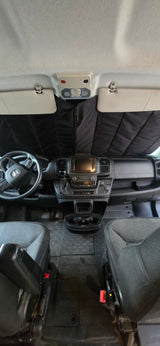 RV rental interior: view of dashboard, steering wheel, and front seats with sunshade installed.