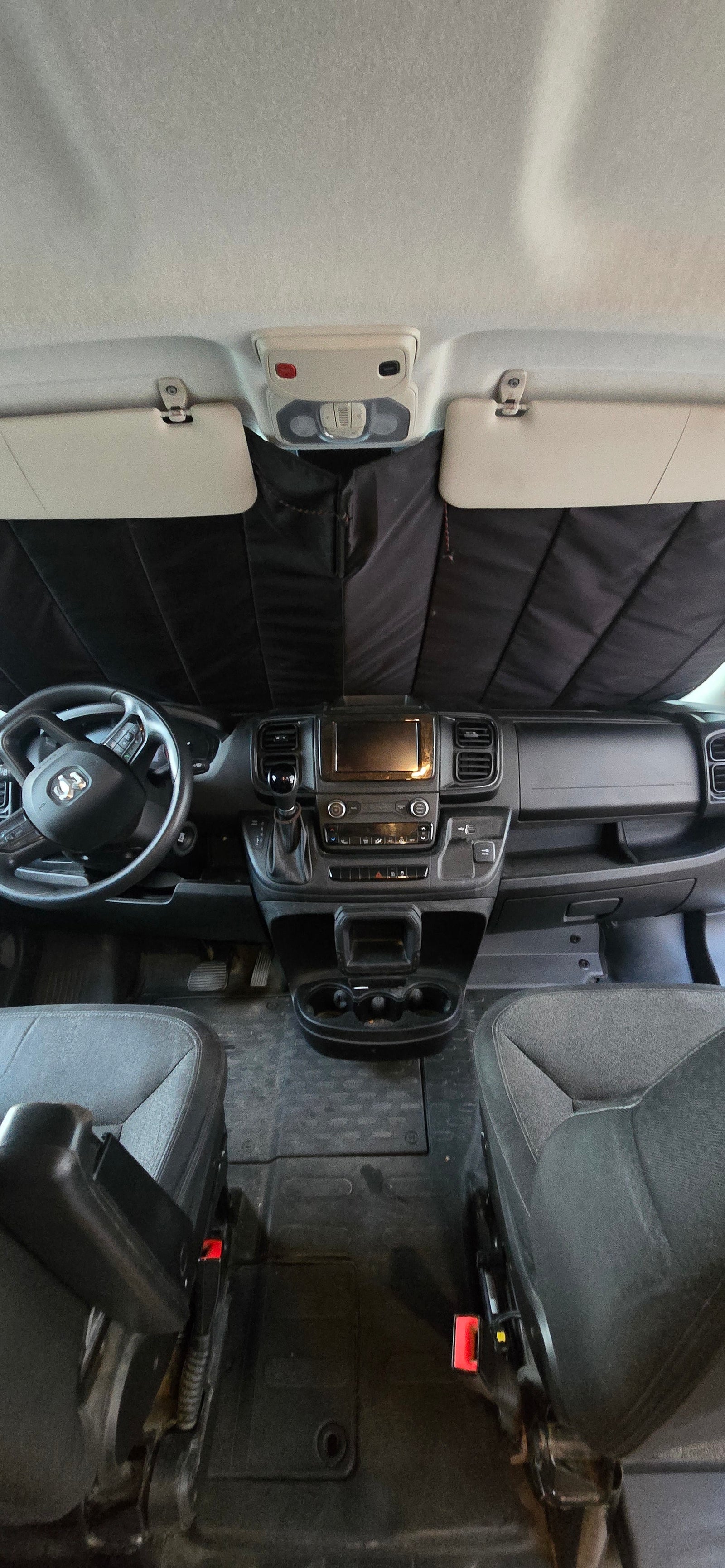 RV rental interior: view of dashboard, steering wheel, and front seats with sunshade installed.