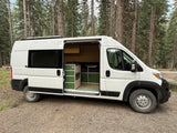 Spacious white camper van with custom green interior, parked in a pine forest, ready for your RV rental adventure.