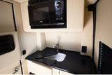This rv rental includes a compact kitchenette with a microwave, sink, and counter for easy meal prep on the road.