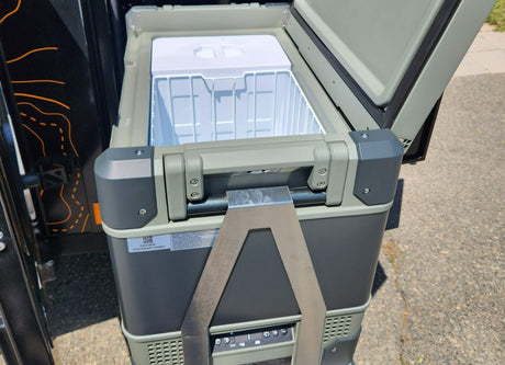 An open Truma portable fridge/freezer unit, ideal for an RV rental. Its internal white bins are ready for off-grid adventures.