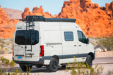 White Winnebago Revel 4x4 camper van with roof rack & ladder, great for an RV rental trip in red rock desert.