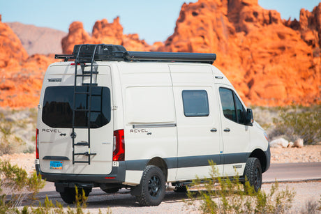 White Winnebago Revel 4x4 camper van with roof rack & ladder, great for an RV rental trip in red rock desert.