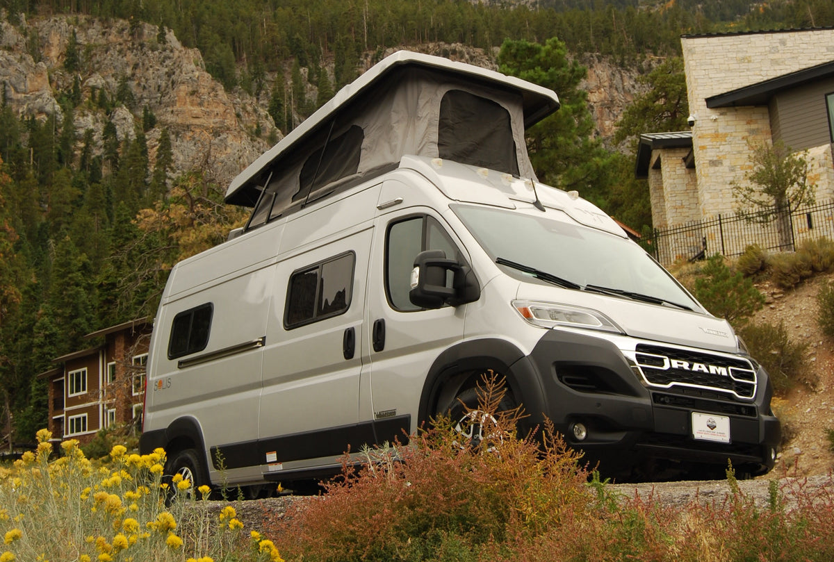 Silver Solis pop-top RV rental parked in a stunning mountain setting with pine trees