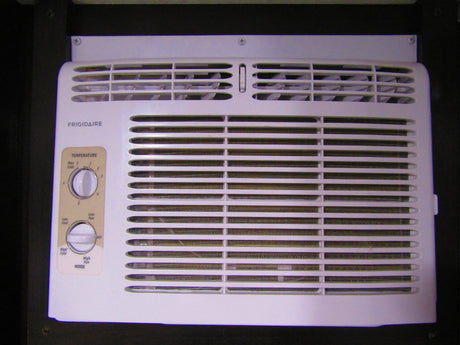 A white Frigidaire air conditioner unit, often found in an RV rental, showing its temperature and mode control dials.