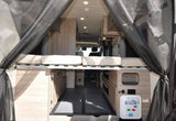 Camper van interior, rear view: elevated bed above flexible storage. Explore your next RV rental adventure.
