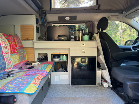 **RV rental** interior: vibrant bed, compact kitchen with fridge, and smart storage solutions for comfortable mobile living.