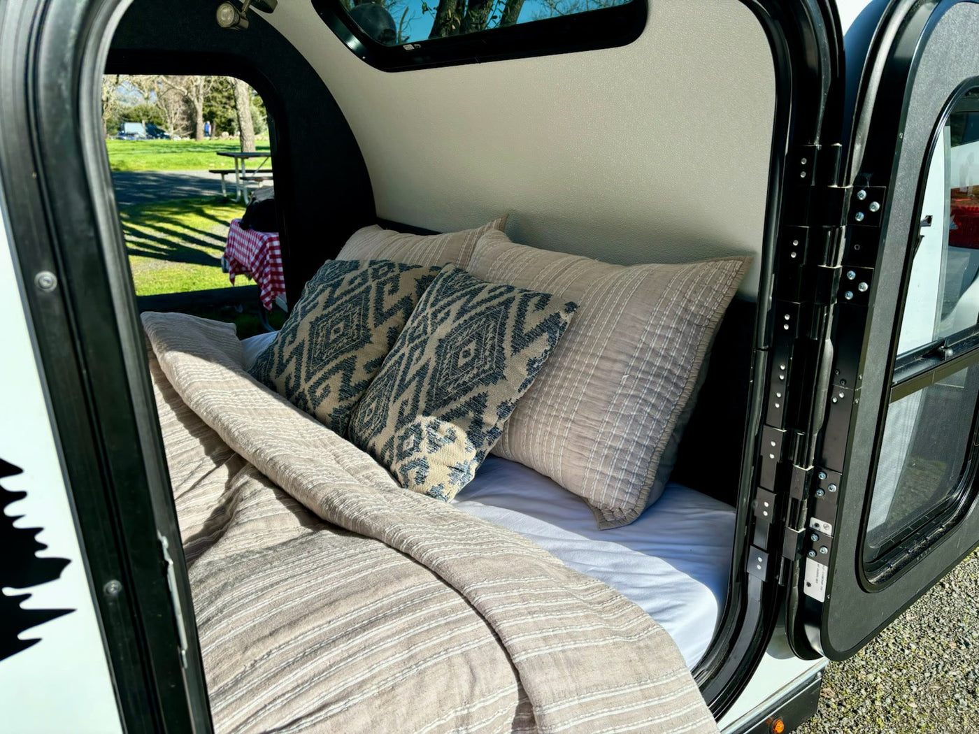  looking out to a green campsite with a picnic table.|Inside an RV rental: overhead diamond plate storage — photo 5