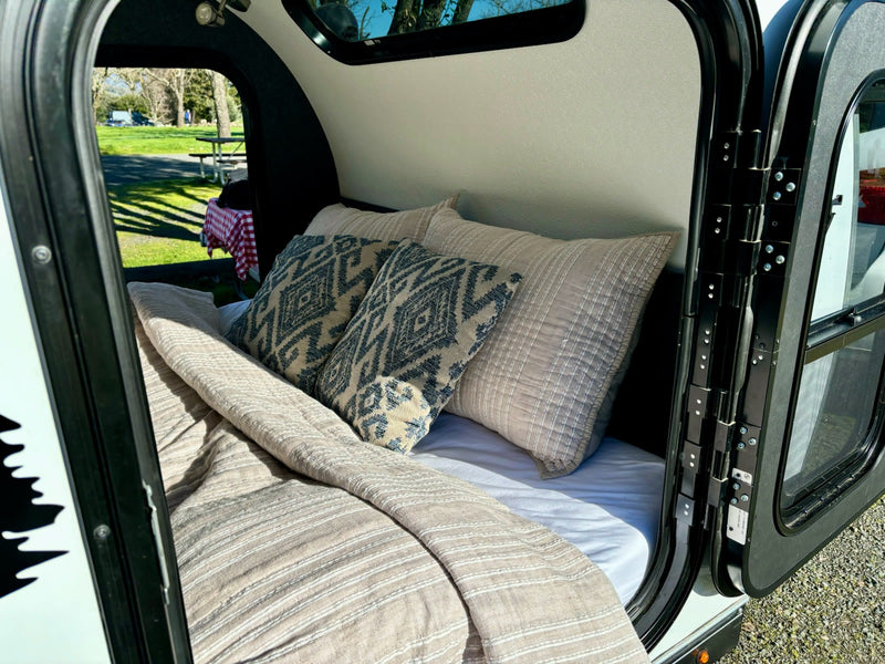  looking out to a green campsite with a picnic table.|Inside an RV rental: overhead diamond plate storage — photo 5