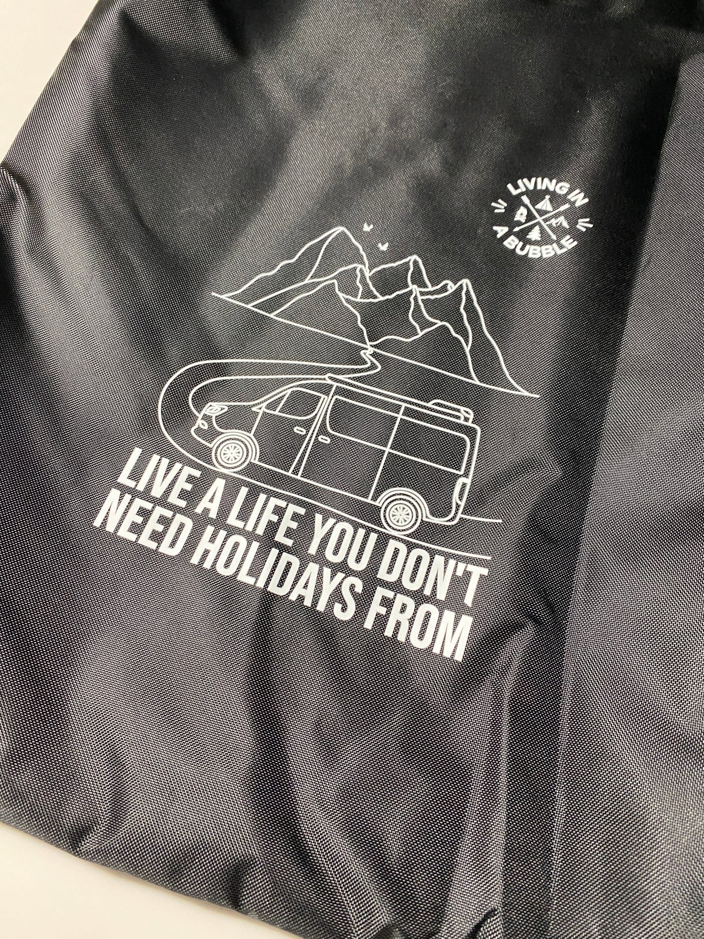 Black fabric with white graphic: an RV, mountains, and text 'Live a life you don't need holidays from.' Great for rv rental!