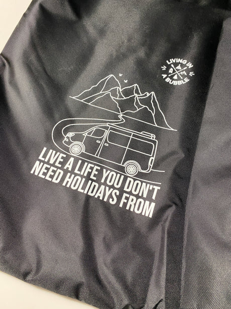 Black fabric with white graphic: an RV, mountains, and text 'Live a life you don't need holidays from.' Great for rv rental!