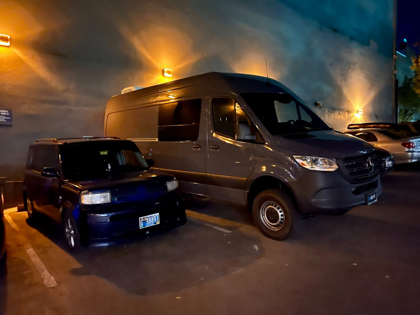  in a parking lot.|Overhead view of an RV rental van parked at night on a street with other vehicles. Features a roof light bar and snorkel. — photo 4