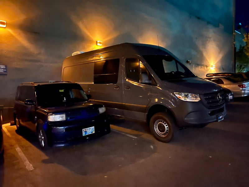  in a parking lot.|Overhead view of an RV rental van parked at night on a street with other vehicles. Features a roof light bar and snorkel. — photo 4