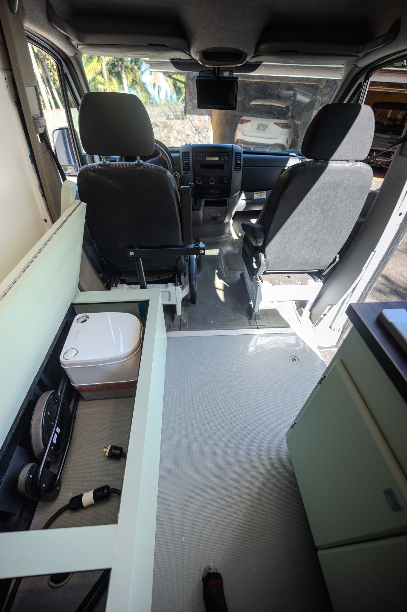 An RV rental interior: front cabin view, with custom cabinetry revealing a Dometic portable toilet and power equipment. — photo 18