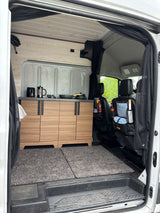 Inside this RV rental: A modern van conversion with wood cabinetry, full kitchenette, and organized front seats. Ready for travel!