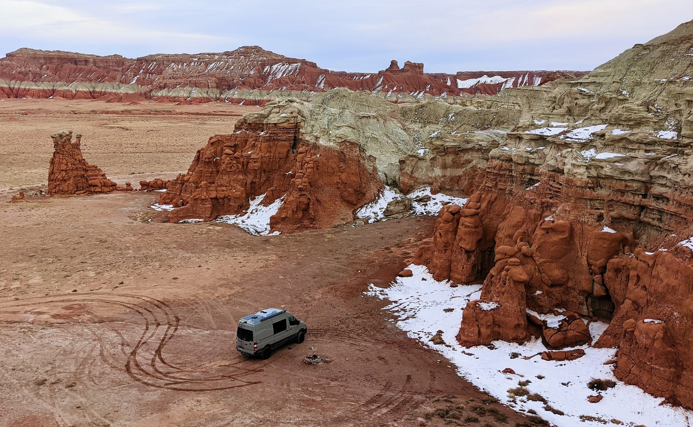 RV rental parked in a striking desert landscape with red and white rock formations and patches of snow.