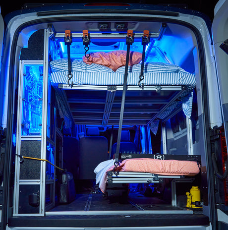 Inside a modern rv rental: custom-built modular bunk beds, bright blue LED lighting, and a mobile creative space for road trips.